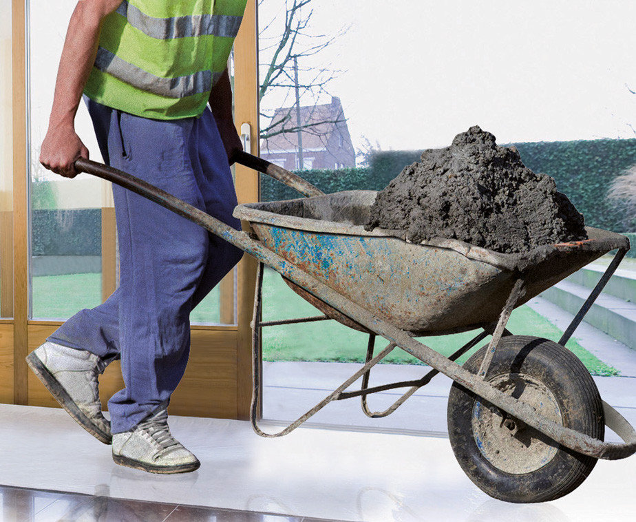 Un artisan transportant une brouette sur la bâche de protection