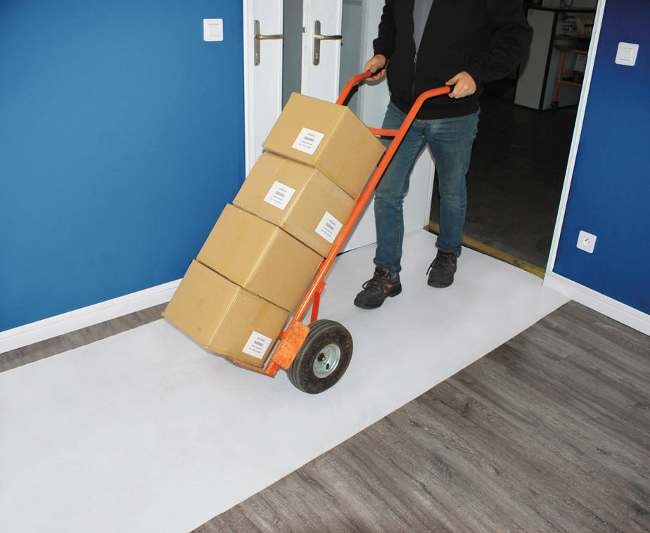 Une personne utilisant un diable sur la bâche de protection auto adhésive