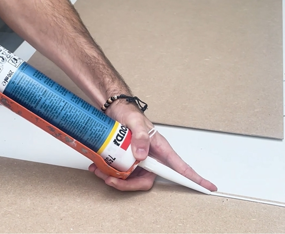 Utilisation du mastic-colle universel avec un pistolet à cartouche pour le collage d'un panneau d'habillage de portes