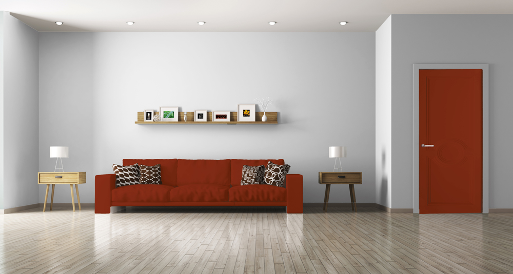 Un grand salon meublé avec un mur blanc, un canapé et une porte de couleur rouge