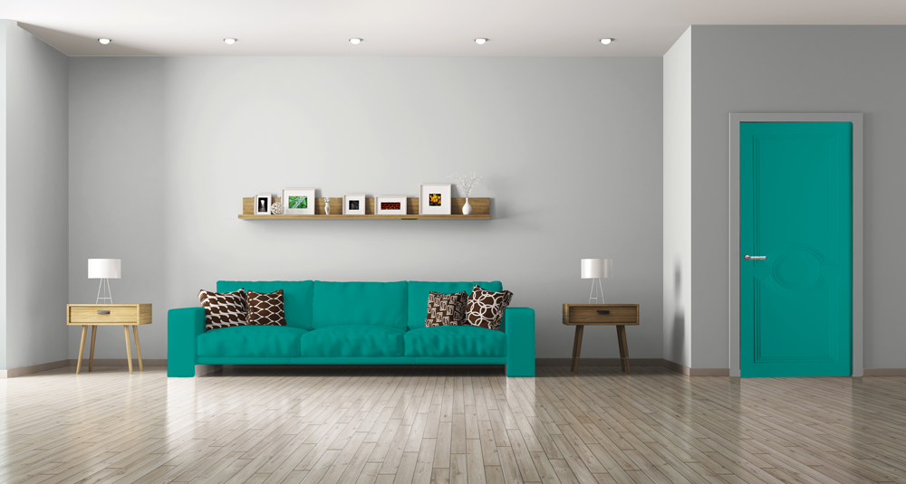 Un grand salon meublé avec un mur blanc, un canapé et une porte de couleur vert d'eau