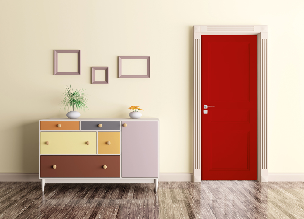 L'entrée d'une pièce comportant un sol avec un parquet, un meuble de plusieurs couleurs et une porte de couleur rouge